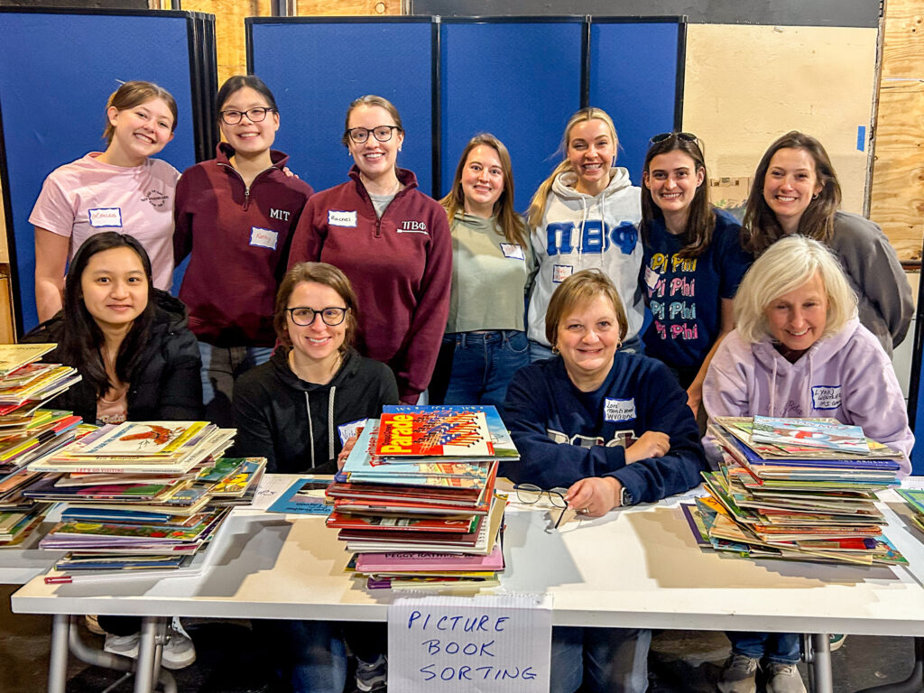 Pi Beta Phi volunteers sitting at a table with piles of books.