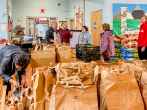 Thomas Bouchard with volunteers packing Thanksgiving provisions into grocery bags in the EPH Afterschool classroom.