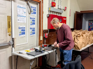 Thomas sets up a table with two laptops for guest registration during the food pantry's Thanksgiving distribution.